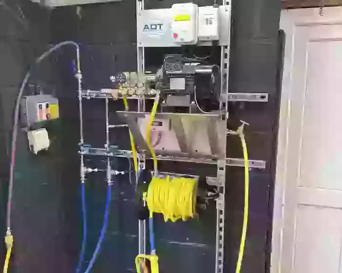 Custom wall-mounted pressure washer system with pump hardware and 20-metre hose reel installed in a vehicle detailer’s workshop in Coalville.